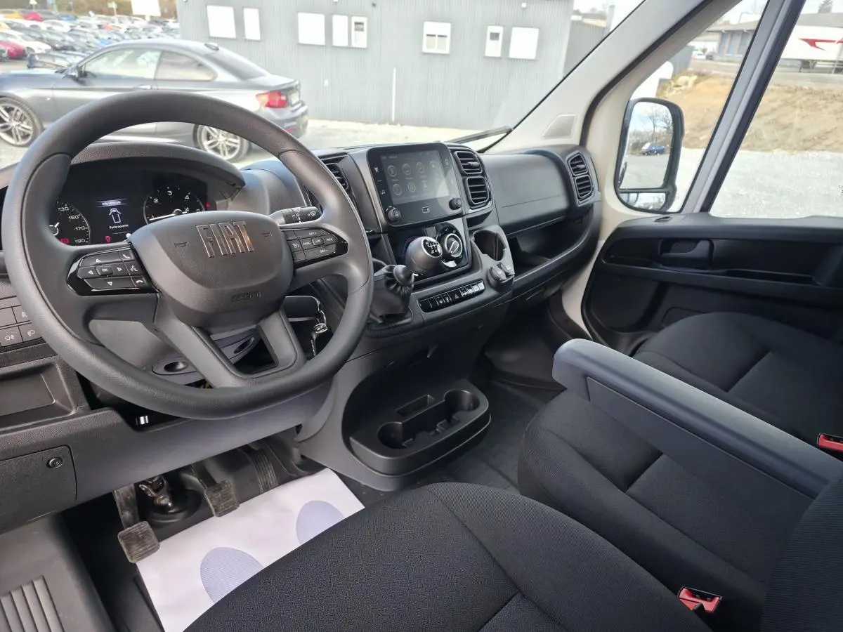 Vue intérieure côté conducteur du Fiat Ducato Fourgon 2025, tableau de bord noir avec écran tactile 7 pouces et volant multifonction.