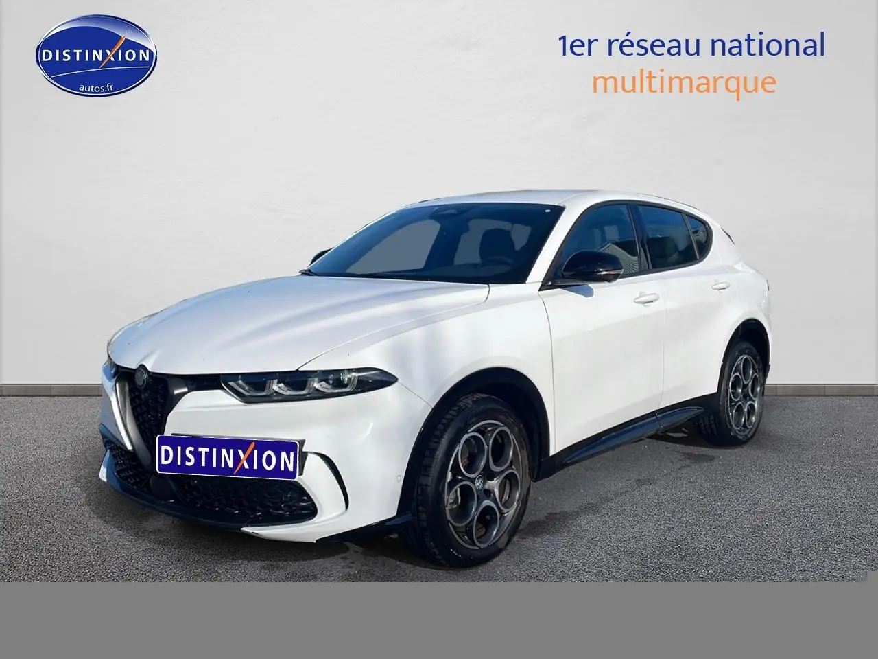 Vue 3/4 avant droite de l'Alfa Romeo Tonale blanc avec jantes alu distinctives et calandre noire sportive.