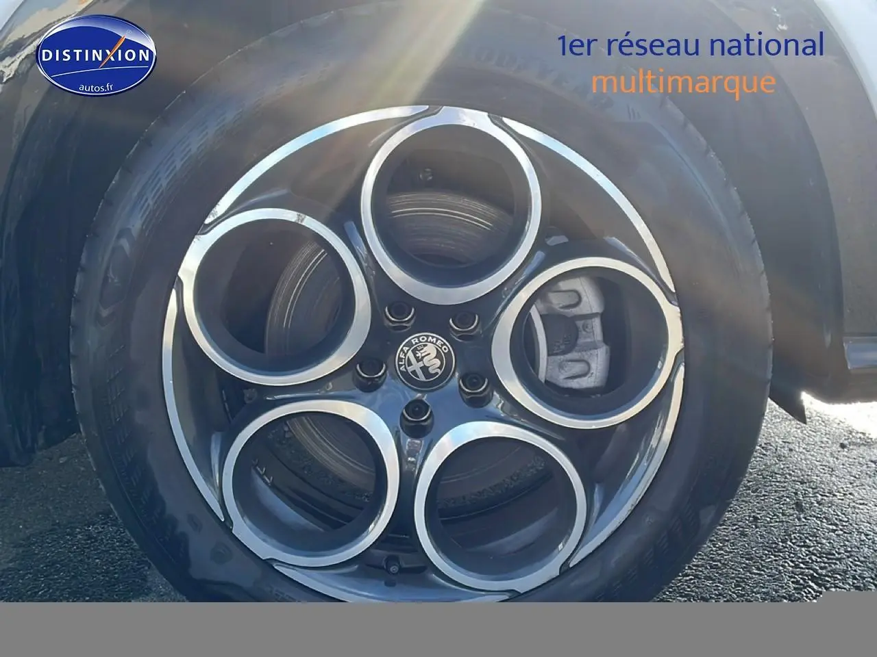 Gros plan sur la jante alu noire et argentée de l'Alfa Romeo Tonale blanche, avec logo central visible.