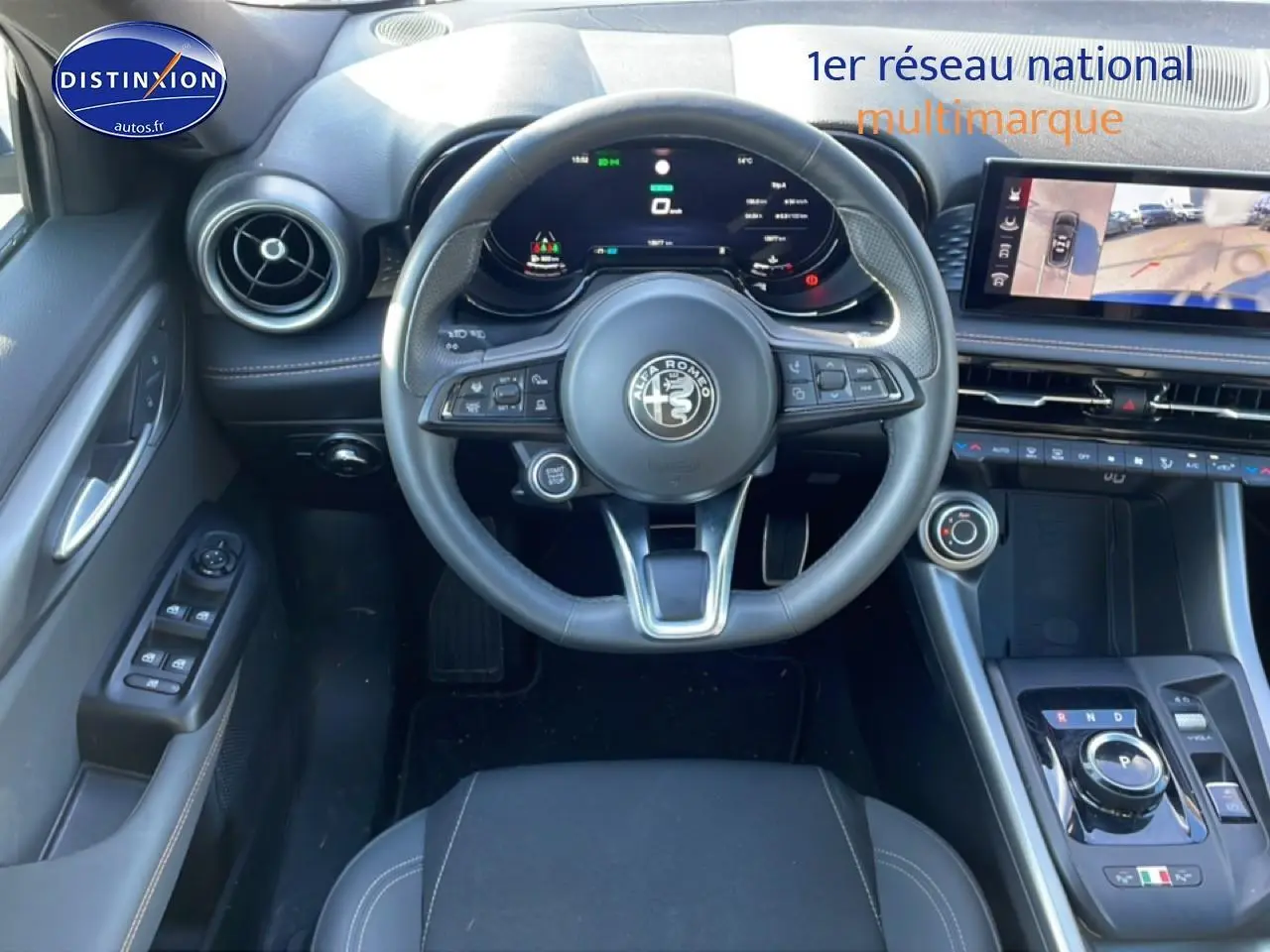 Vue intérieure frontale de l'Alfa Romeo Tonale blanc, volant cuir sport et écran tactile avec caméra de recul.