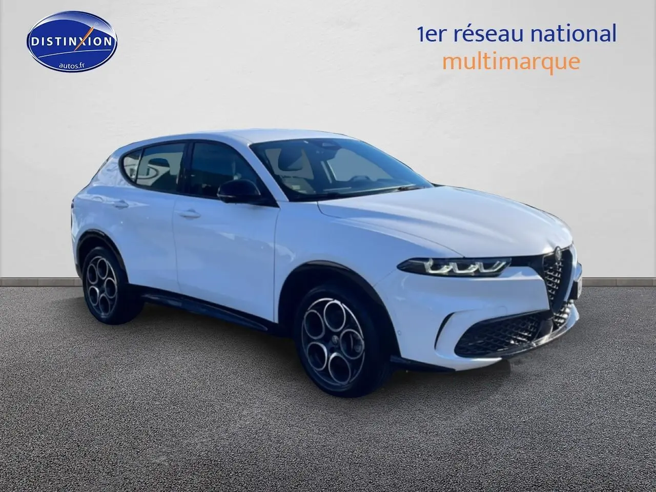 Vue 3/4 avant droite d’un Alfa Romeo Tonale blanc 2025 avec jantes alu et calandre distinctive en V.