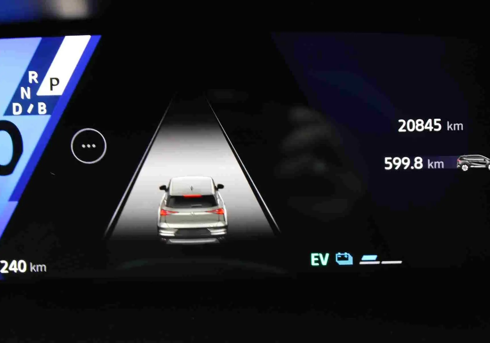 Affichage numérique du tableau de bord montrant un véhicule blanc vu de l'arrière en mode hybride avec compteur à zéro.