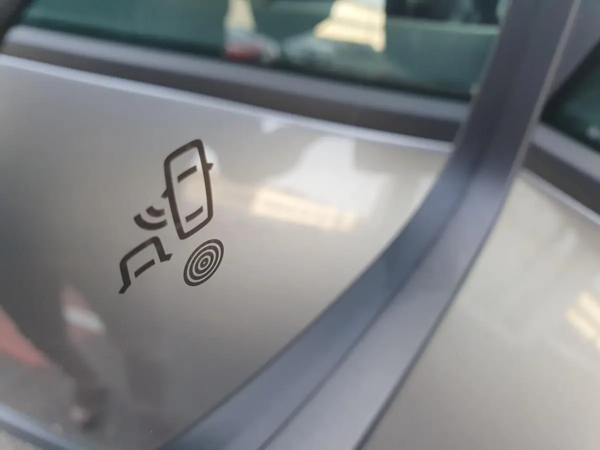 Détail du logo d’alerte de détection d’angle mort sur la vitre côté droit d’un Dacia Bigster gris schiste.