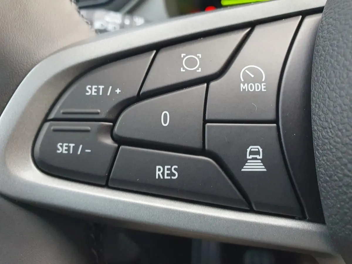 Gros plan sur les commandes noires du volant du Dacia Bigster 2026, boutons de régulateur et mode de conduite.