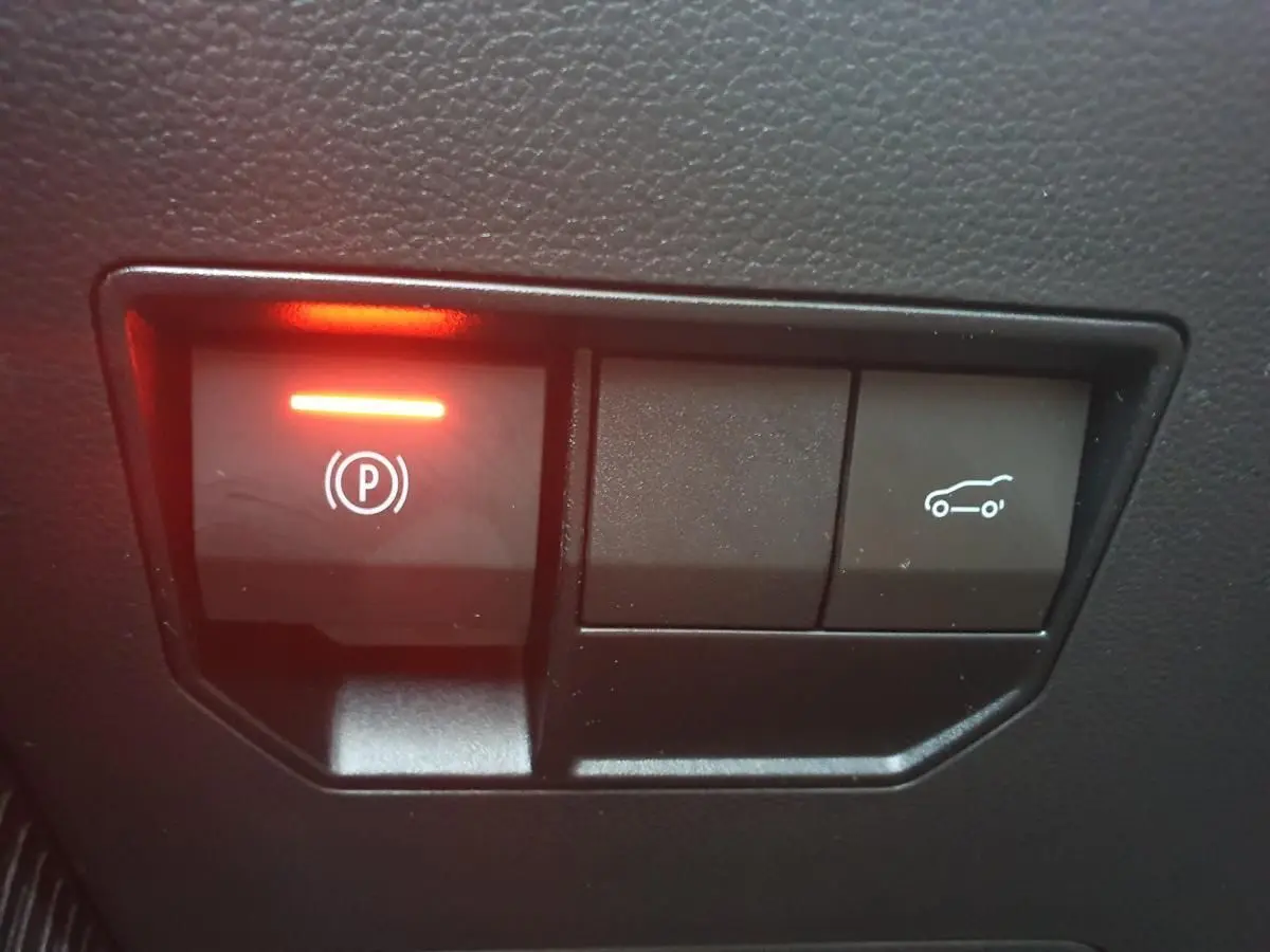 Gros plan sur les boutons de commande du frein de parking et ouverture du coffre dans l’habitacle du Dacia Bigster gris schiste.