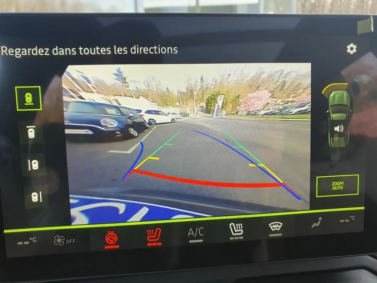 Vue arrière caméra de recul du Dacia Bigster gris schiste avec lignes de guidage colorées et capteurs de stationnement actifs.