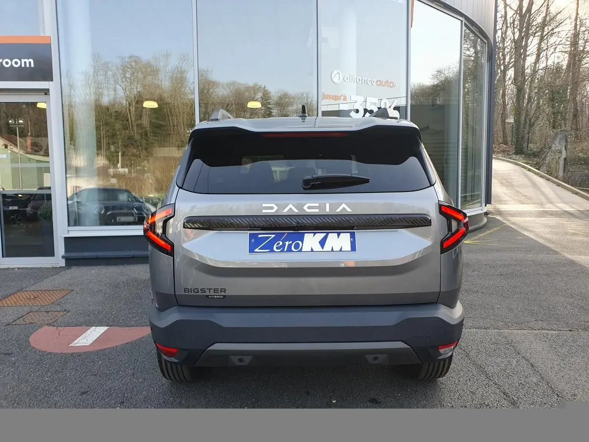 Vue arrière d’un Dacia Bigster gris schiste avec feux LED en forme de C et logo DACIA lumineux.