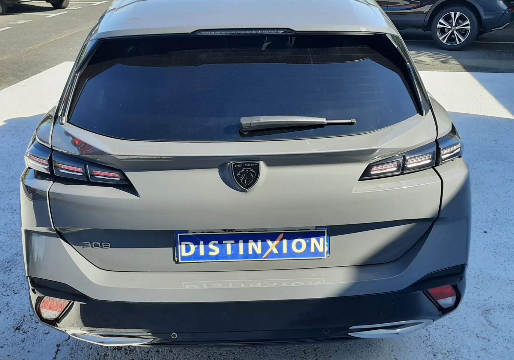 Vue arrière d'une Peugeot 308 SW Hybrid gris sélénium métal, avec feux LED et logo lion distinctif sur le hayon.