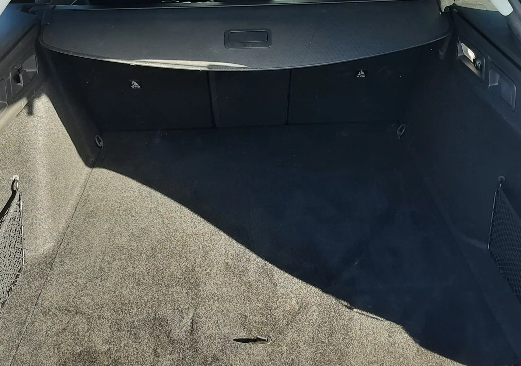 Vue intérieure du coffre spacieux et propre de la Peugeot 308 SW Hybrid 145ch gris Selenium Metal, avec cache-bagages déployé.