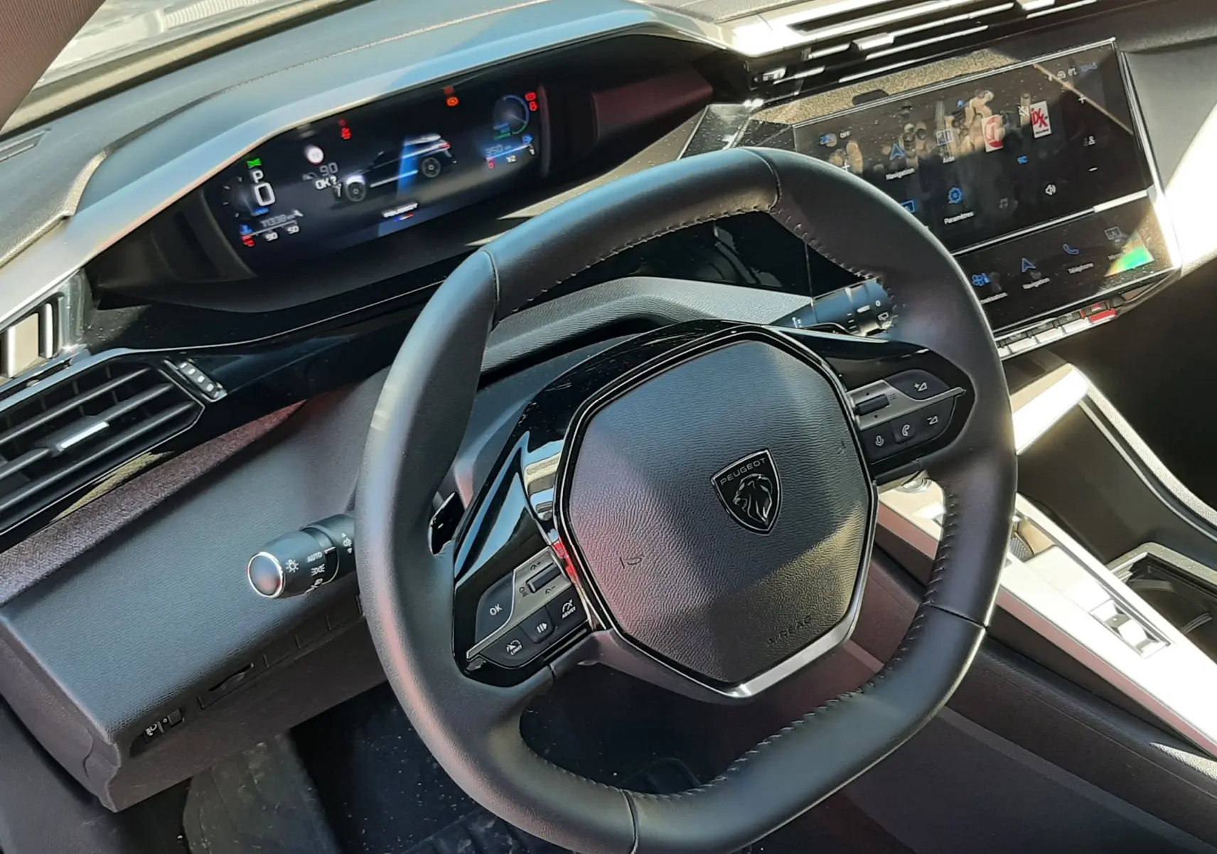 Vue intérieure du volant et tableau de bord numérique de la Peugeot 308 SW Hybrid 2025, ambiance moderne et finition noire.