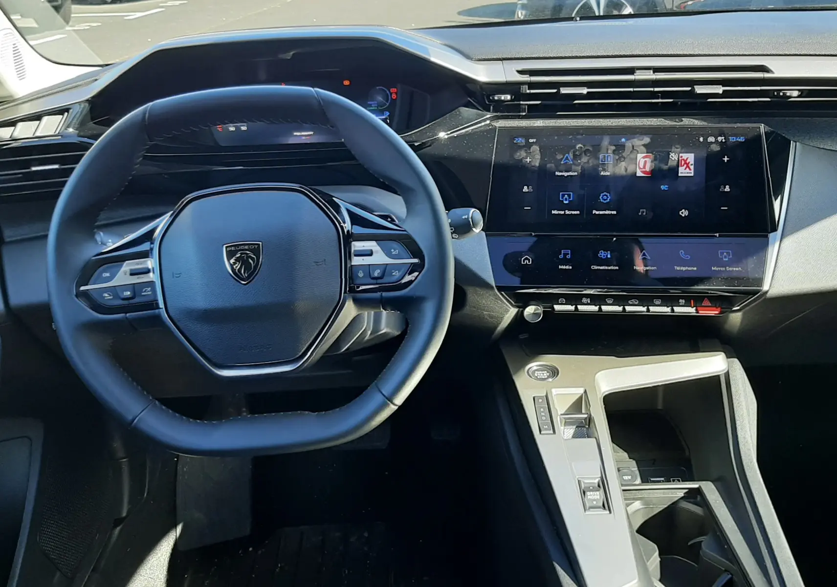 Vue intérieure centrée sur le volant et l’écran tactile du tableau de bord de la Peugeot 308 SW Hybrid 2025.