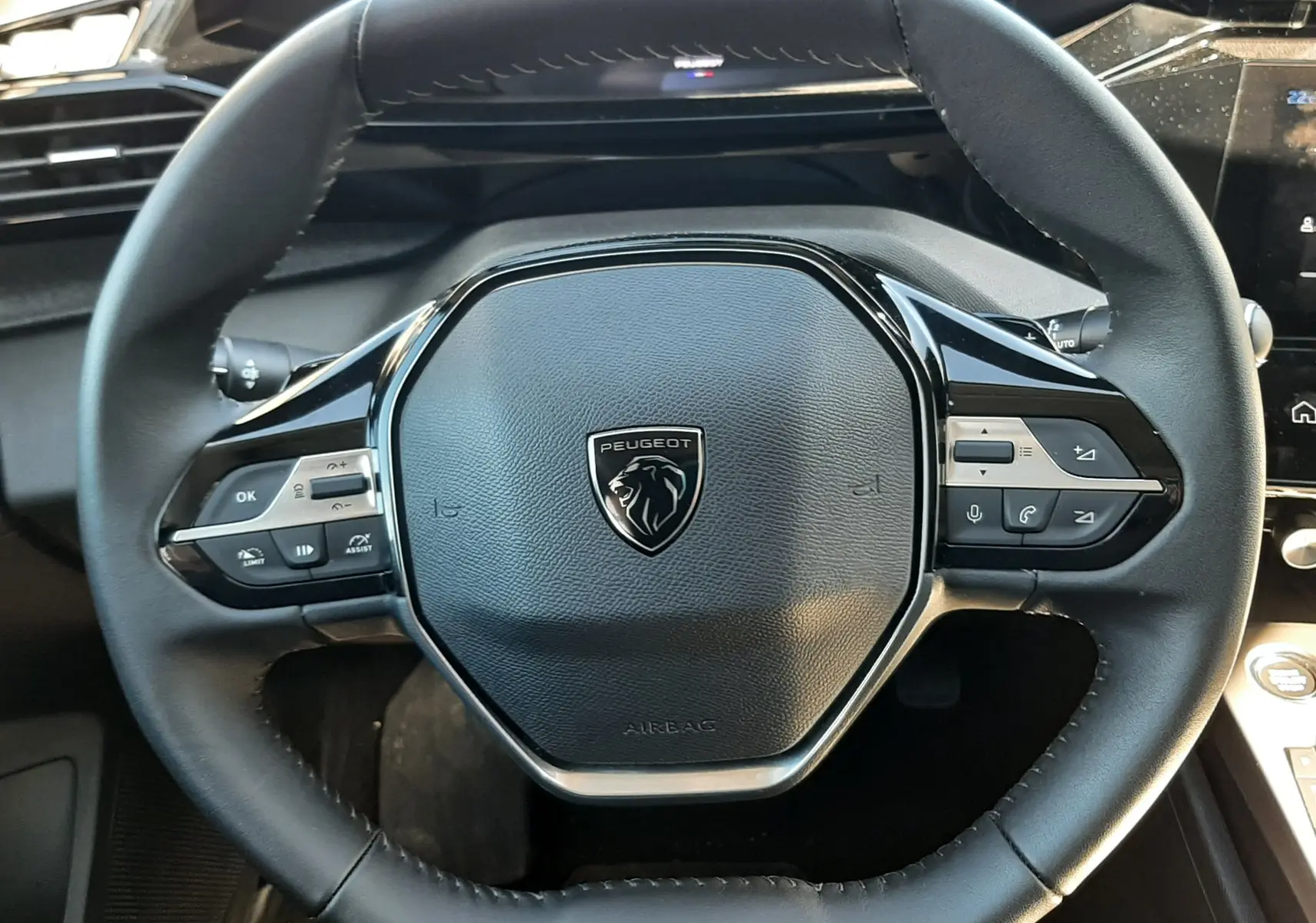 Vue rapprochée du volant noir du Peugeot 308 SW Hybrid 145ch 2025, avec commandes intégrées et logo lion central.