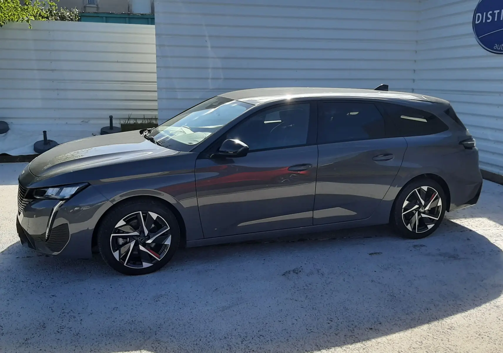 Peugeot 308 SW Hybrid gris selenium métal vue de profil côté gauche, avec jantes alliage noires et rouges.