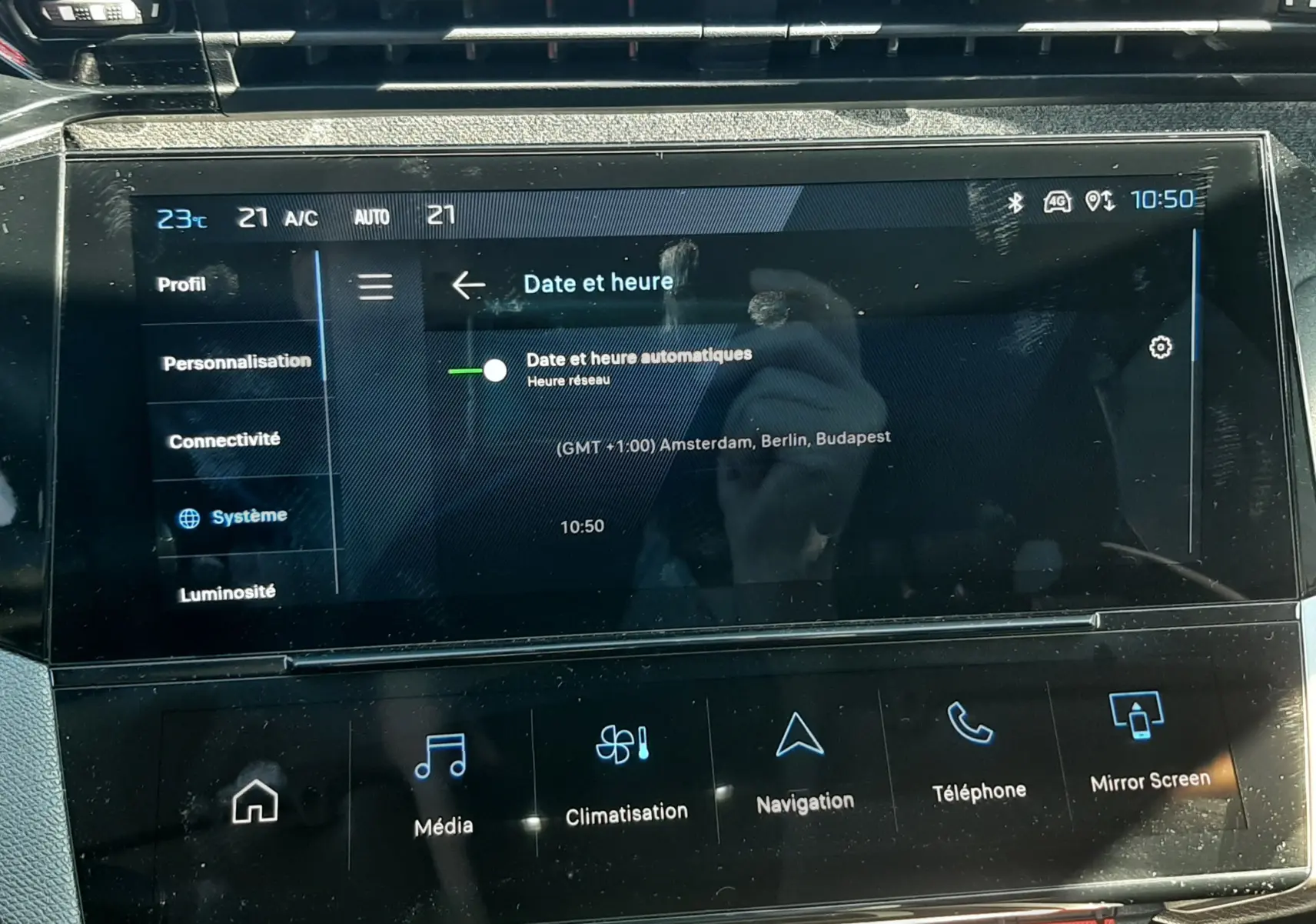 Vue rapprochée de l’écran tactile central du tableau de bord de la Peugeot 308 SW Hybrid 2025, affichant les réglages de date et heure.