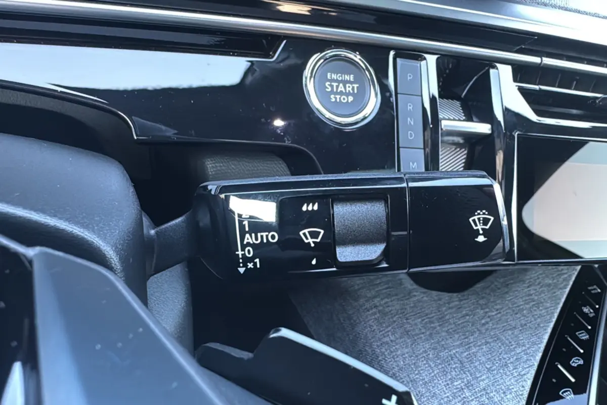 Gros plan sur la commande d’essuie-glace et bouton start/stop du tableau de bord du Peugeot 3008 hybride noir perla nera 2025.