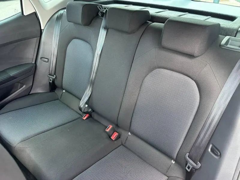 Vue intérieure de la banquette arrière en tissu gris du SEAT Arona 2025, avec ceintures de sécurité visibles.