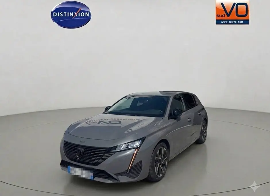 Peugeot 308 gris vue 3/4 avant droit, avec jantes alliage 17 pouces et feux LED distinctifs verticaux.