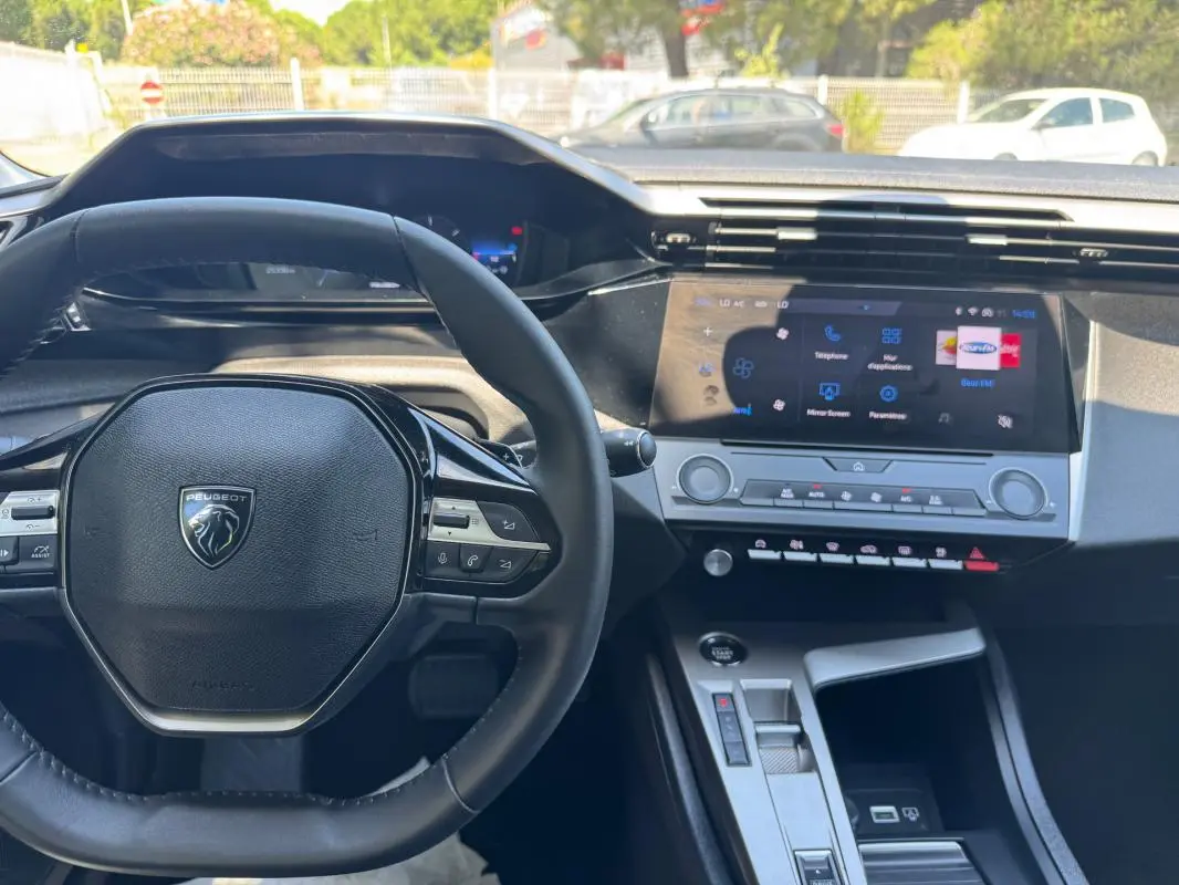 Vue intérieure centrée sur le volant Peugeot et le tableau de bord numérique de la 308 gris 2025.