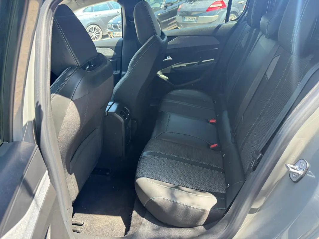 Vue intérieure arrière côté gauche de la Peugeot 308 gris 2025, montrant les sièges en tissu et cuir avec appuie-têtes.