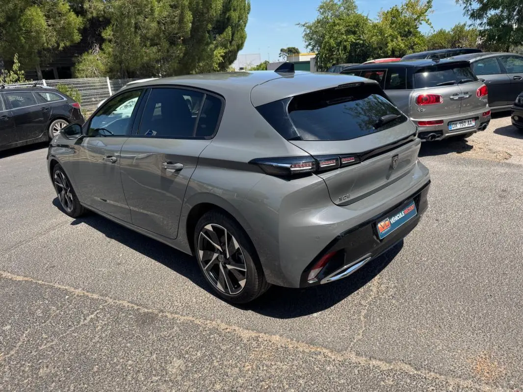 Vue 3/4 arrière droite d'une Peugeot 308 gris métallisé 2025 avec jantes alliage 17 pouces et feux arrière LED distinctifs.