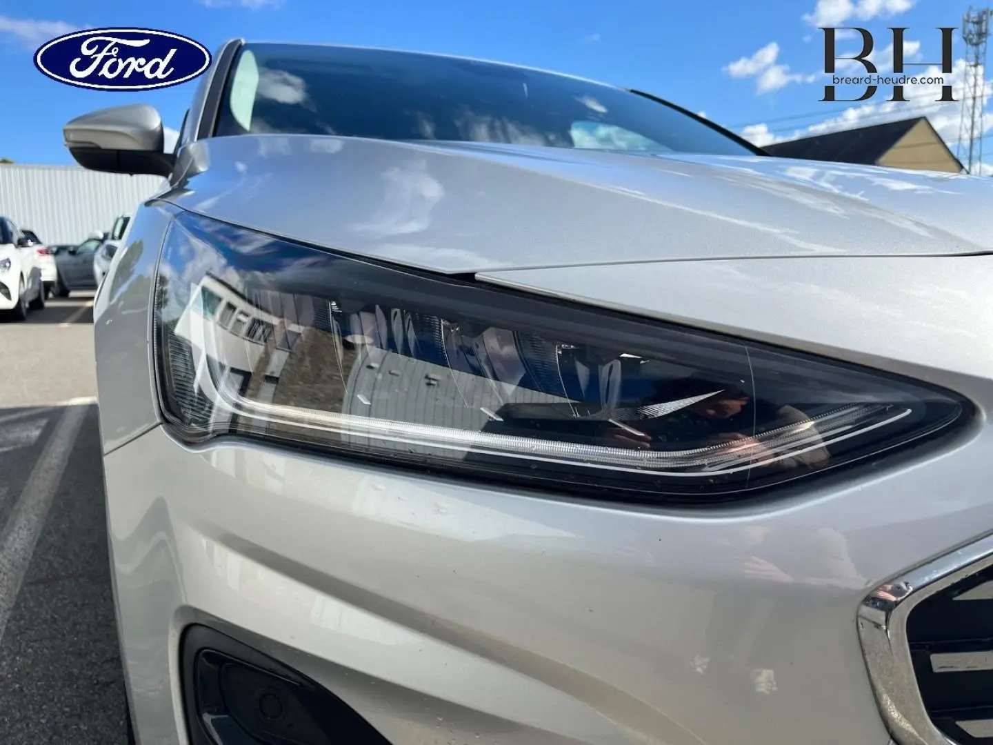 Gros plan sur le phare avant droit d'une Ford Focus gris lunaire métallisé, soulignant les détails modernes du bloc optique.