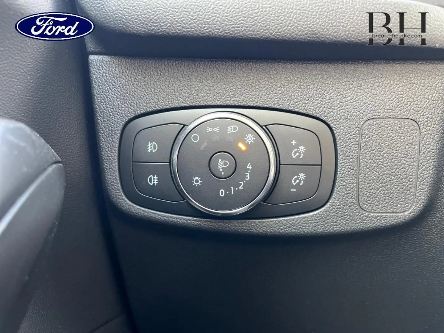 Gros plan sur le bouton de réglage des phares dans l’habitacle noir d’une Ford Focus Titanium X 2022.