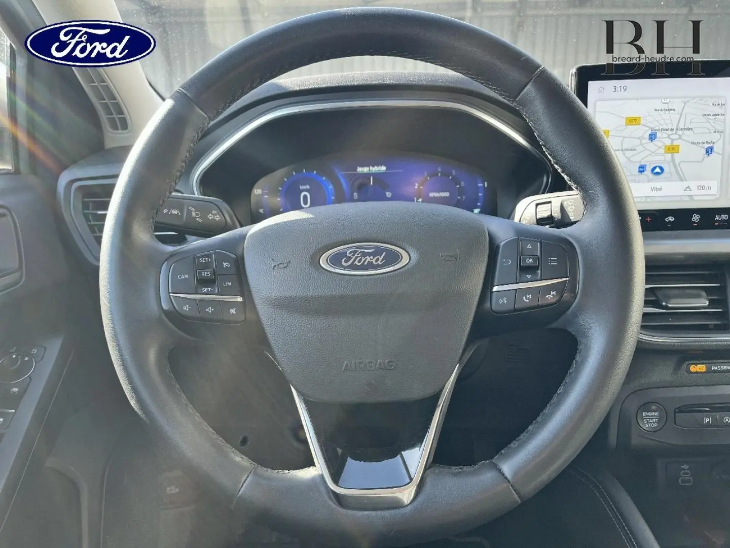Vue rapprochée du volant en cuir noir de la Ford Focus 2022 avec commandes intégrées et écran tactile GPS visible.