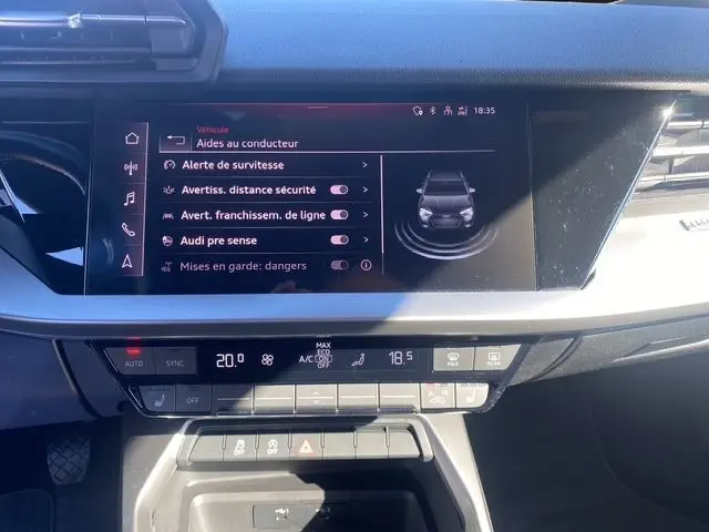 Vue rapprochée de l'écran central et de la console d'une Audi A3 Sportback 2021, affichant les aides à la conduite.