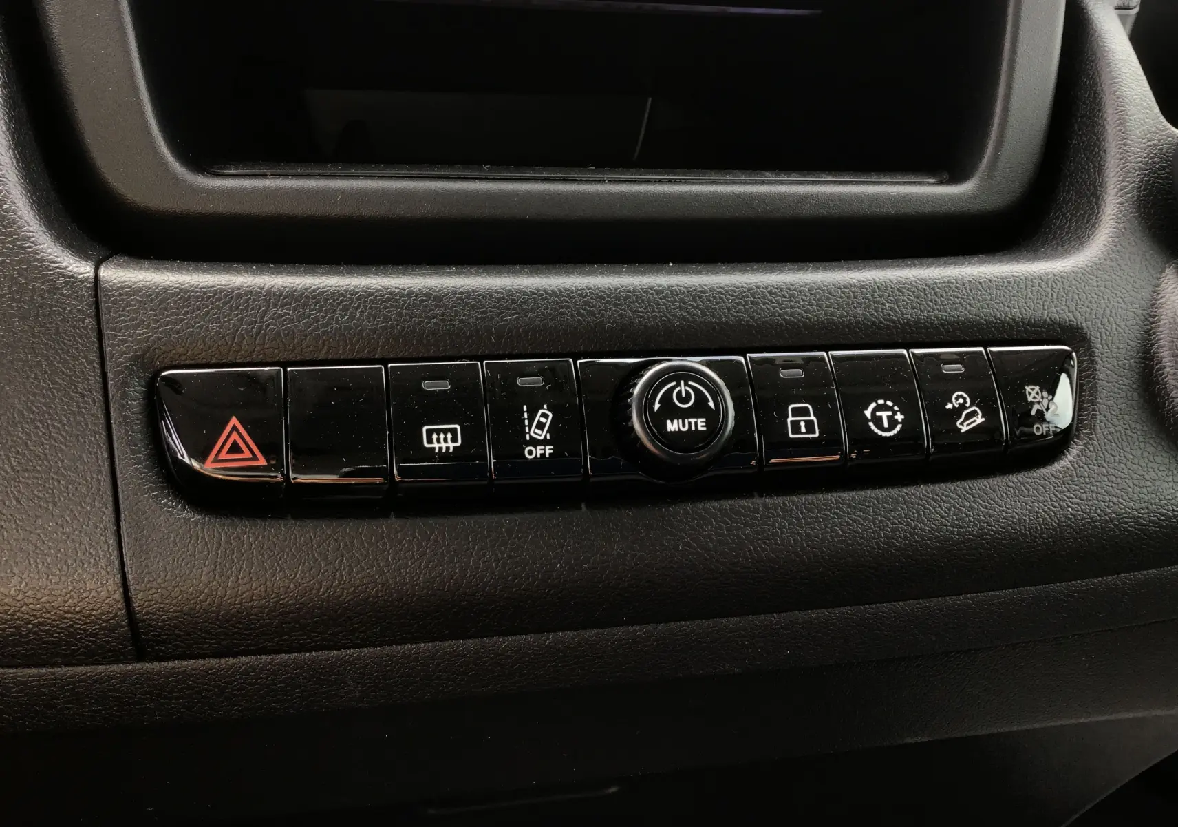 Gros plan sur la rangée de boutons noirs du tableau de bord du Peugeot Boxer Fourgon blanc, avec bouton mute central.
