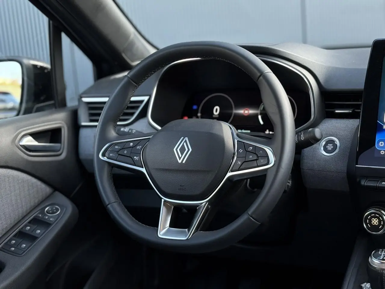 Vue intérieure centrée sur le volant multifonction noir de la Renault Clio 2025 avec tableau de bord numérique.