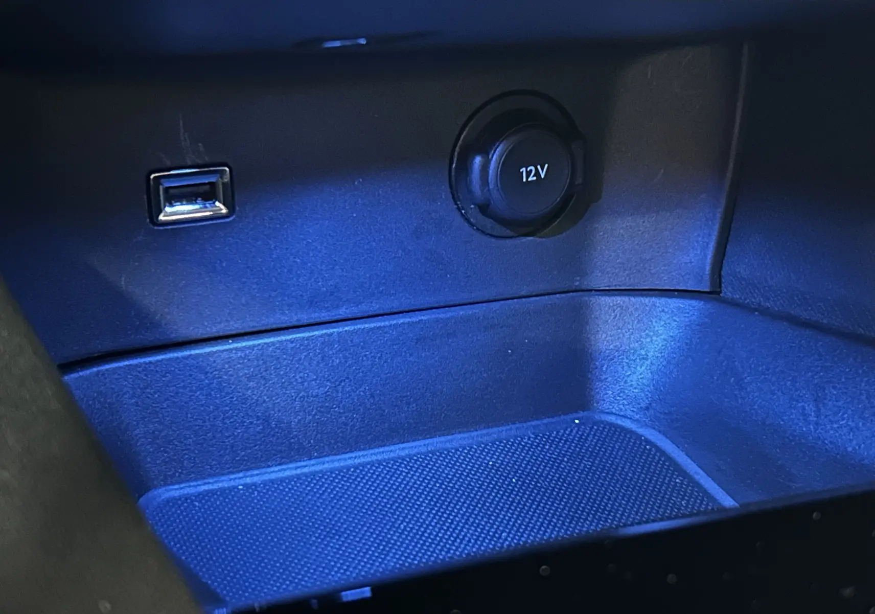 Gros plan sur la prise 12V et port USB dans le rangement central intérieur du Peugeot 3008 gris Artense toit noir.