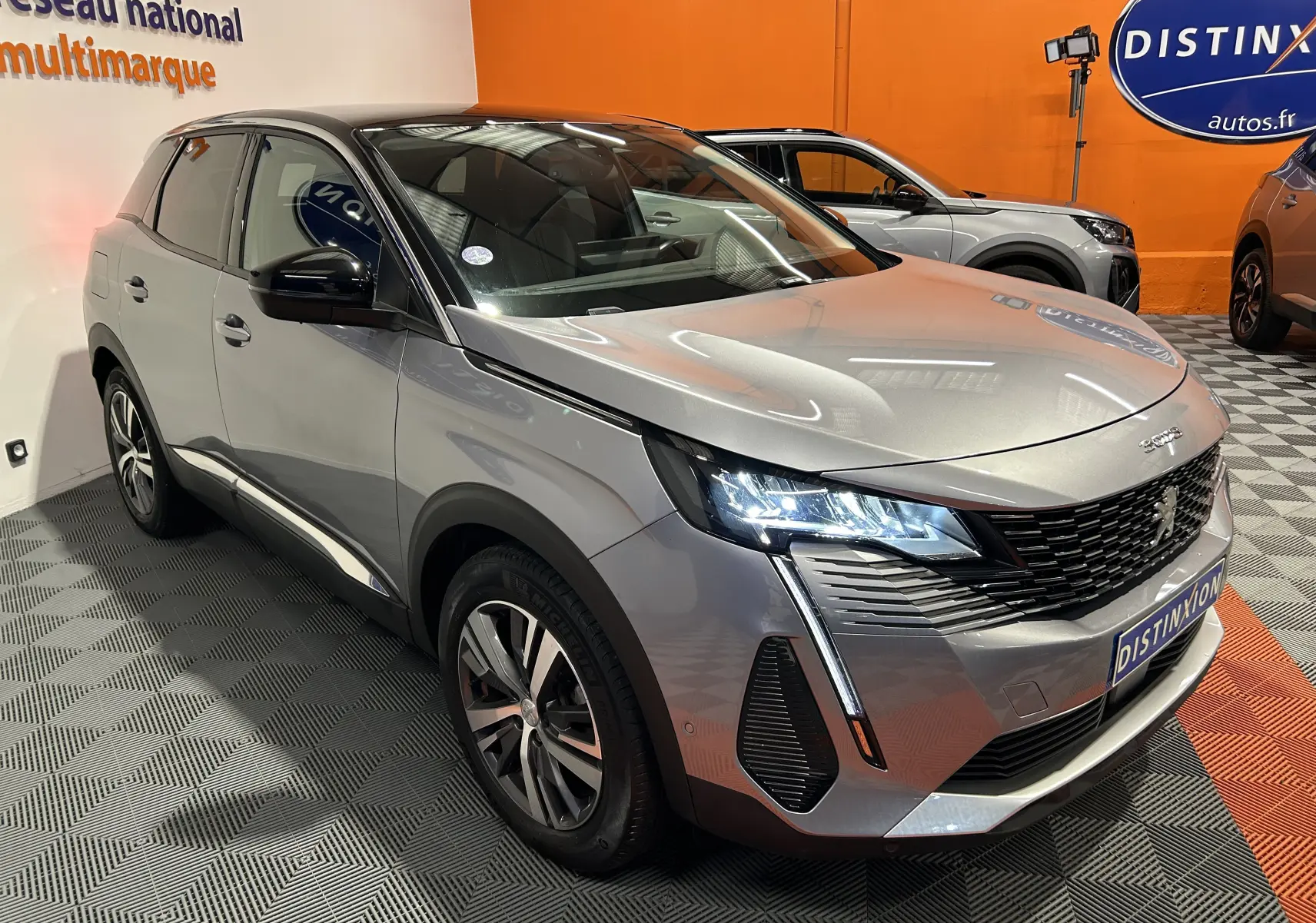 Peugeot 3008 gris Artense avec toit noir, vue 3/4 avant droit, phares allumés et attelage visible.