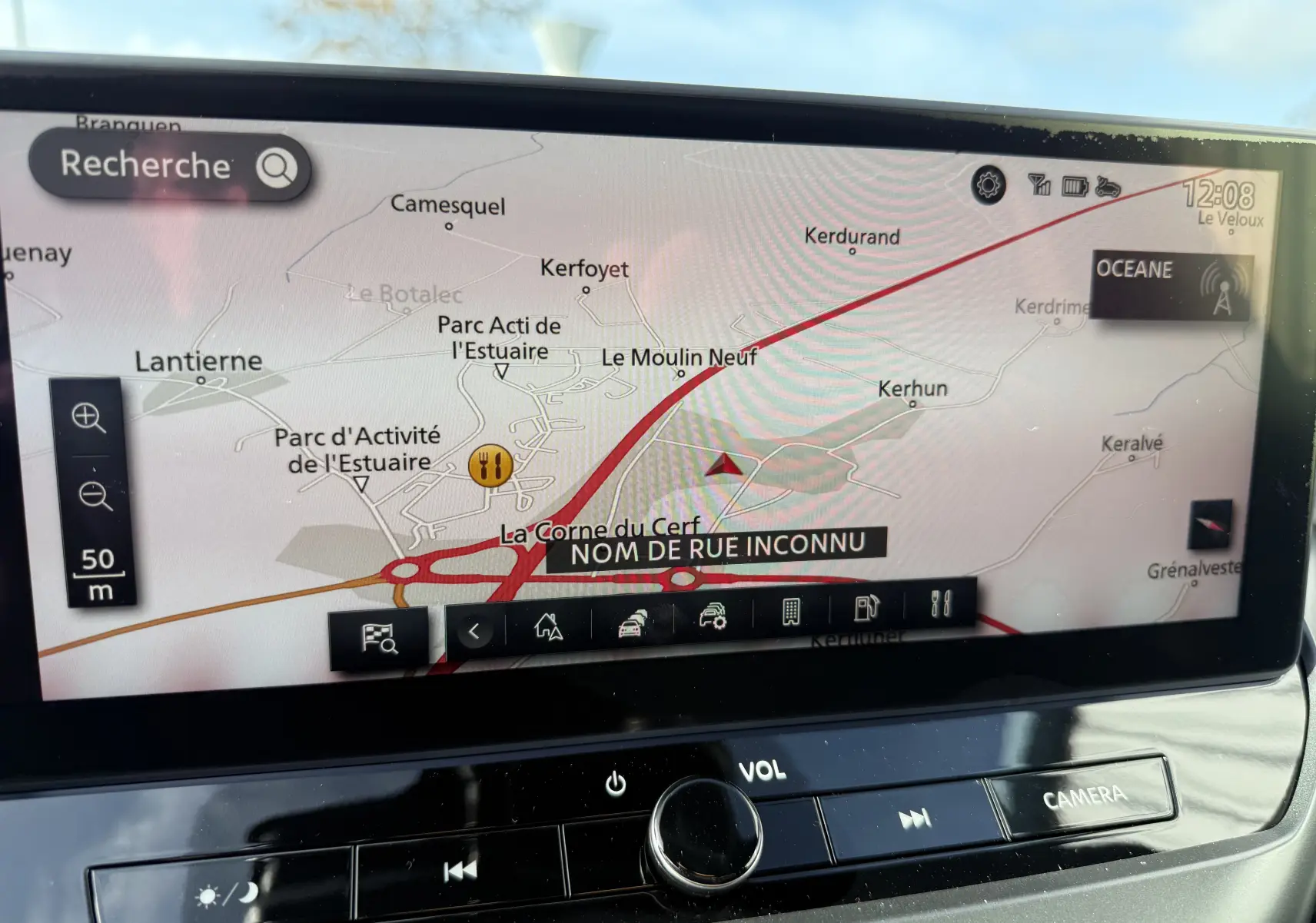 Écran tactile du système de navigation du Nissan Juke rouge Fuji, affichant une carte routière avec options et commandes intégrées.