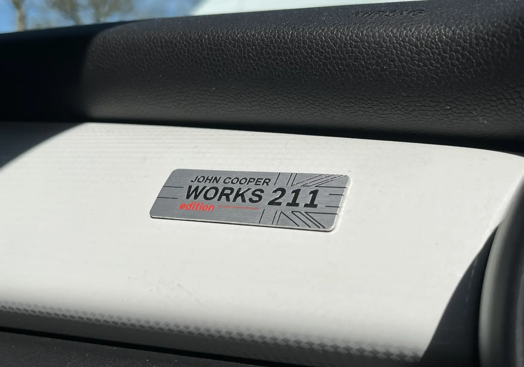 Plaque intérieure John Cooper Works 211 édition sur tableau de bord blanc et noir d'une MINI Cabriolet F57 bleu.