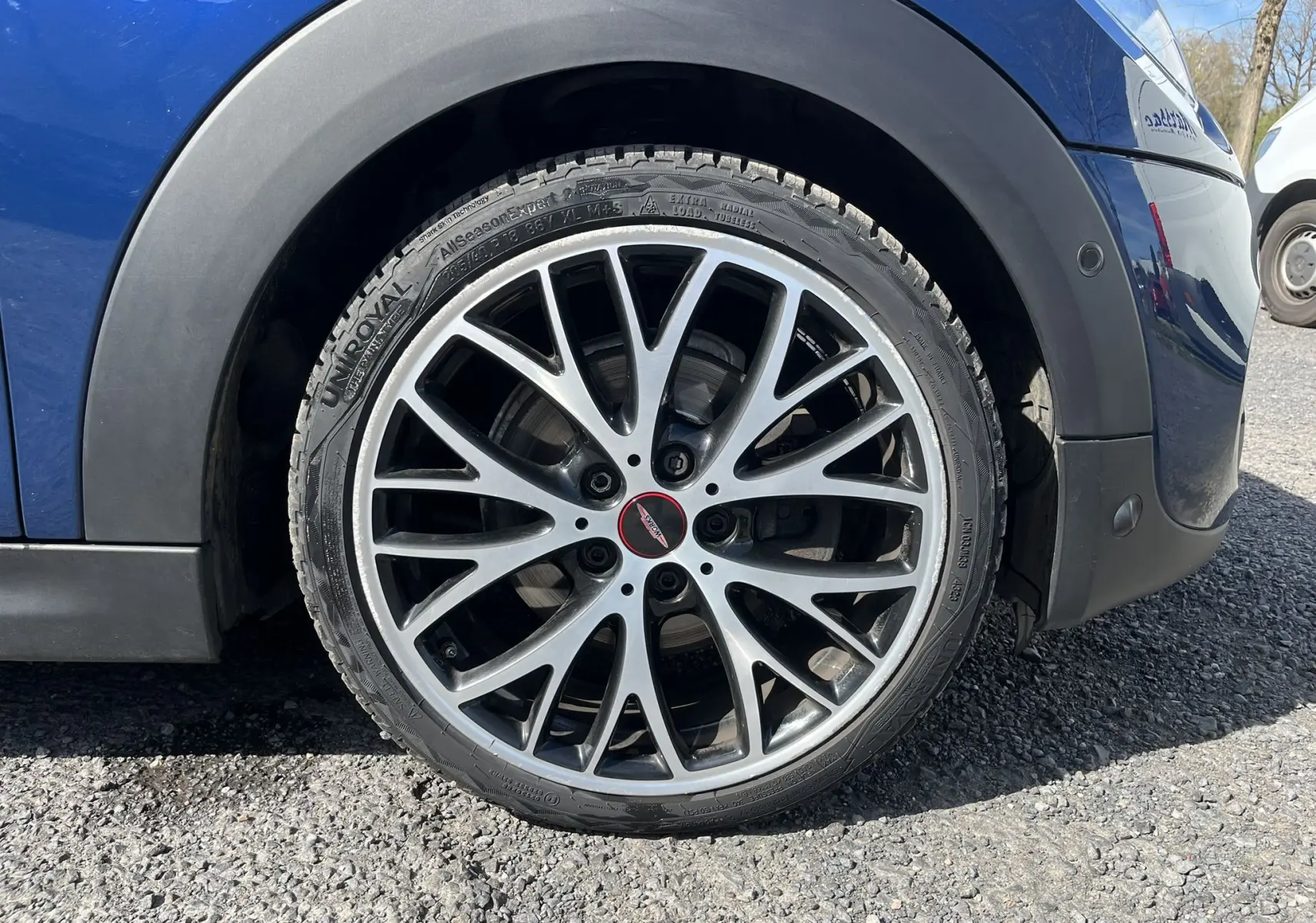 Gros plan sur la roue avant droite d'une MINI Cabriolet F57 Cooper S bleu, avec jante alliage multibranches et logo John Cooper Works.