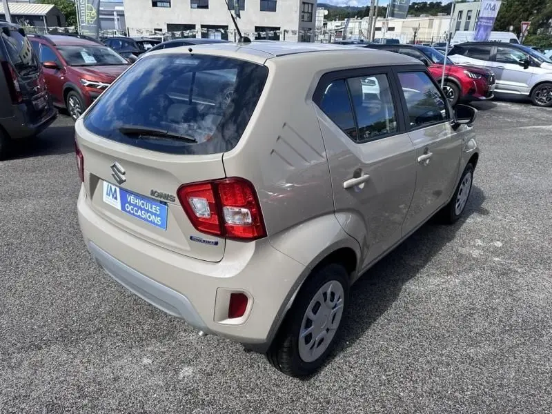 Vue 3/4 arrière droite d'une Suzuki Ignis beige 2023, compacte avec feux arrière carrés et jantes acier.