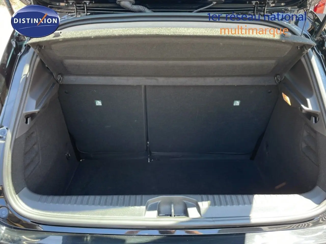 Coffre ouvert vu de l'arrière d'une Renault Clio noir étoile métal, montrant l'espace de rangement vide.