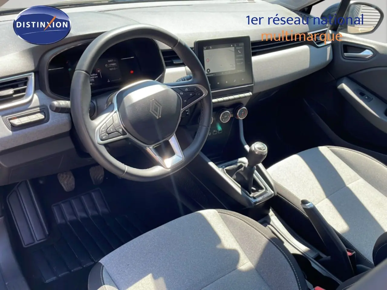 Vue intérieure avant de la Renault Clio V BluedCi 100ch Evolution 2025, volant cuir, tableau de bord moderne et sièges tissu gris.