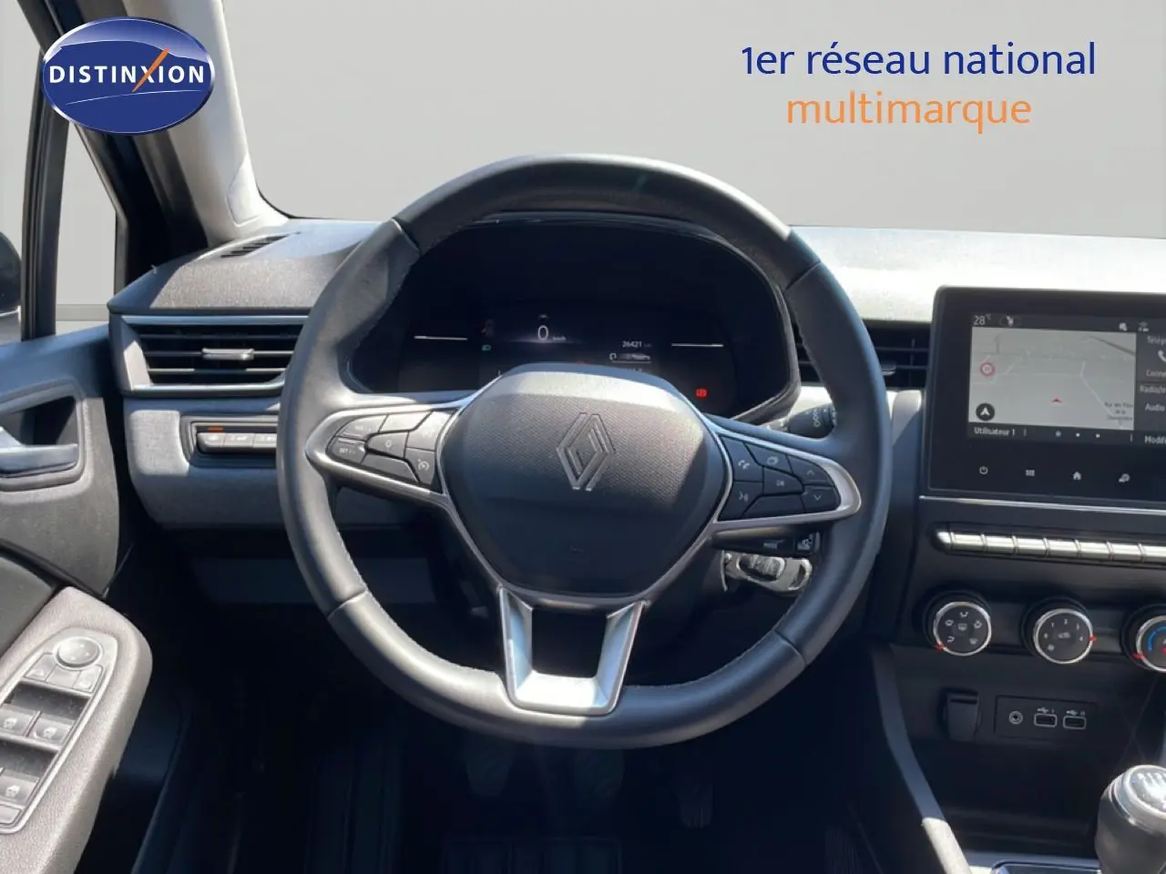 Vue intérieure centrée sur le volant cuir noir de la Renault Clio 2025 avec tableau de bord digital et écran tactile.