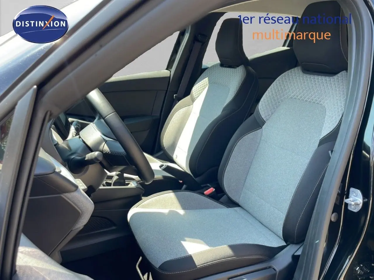 Vue intérieure côté conducteur de la Renault Clio noire étoile métal, mettant en valeur les sièges tissu gris et noir au design moderne.