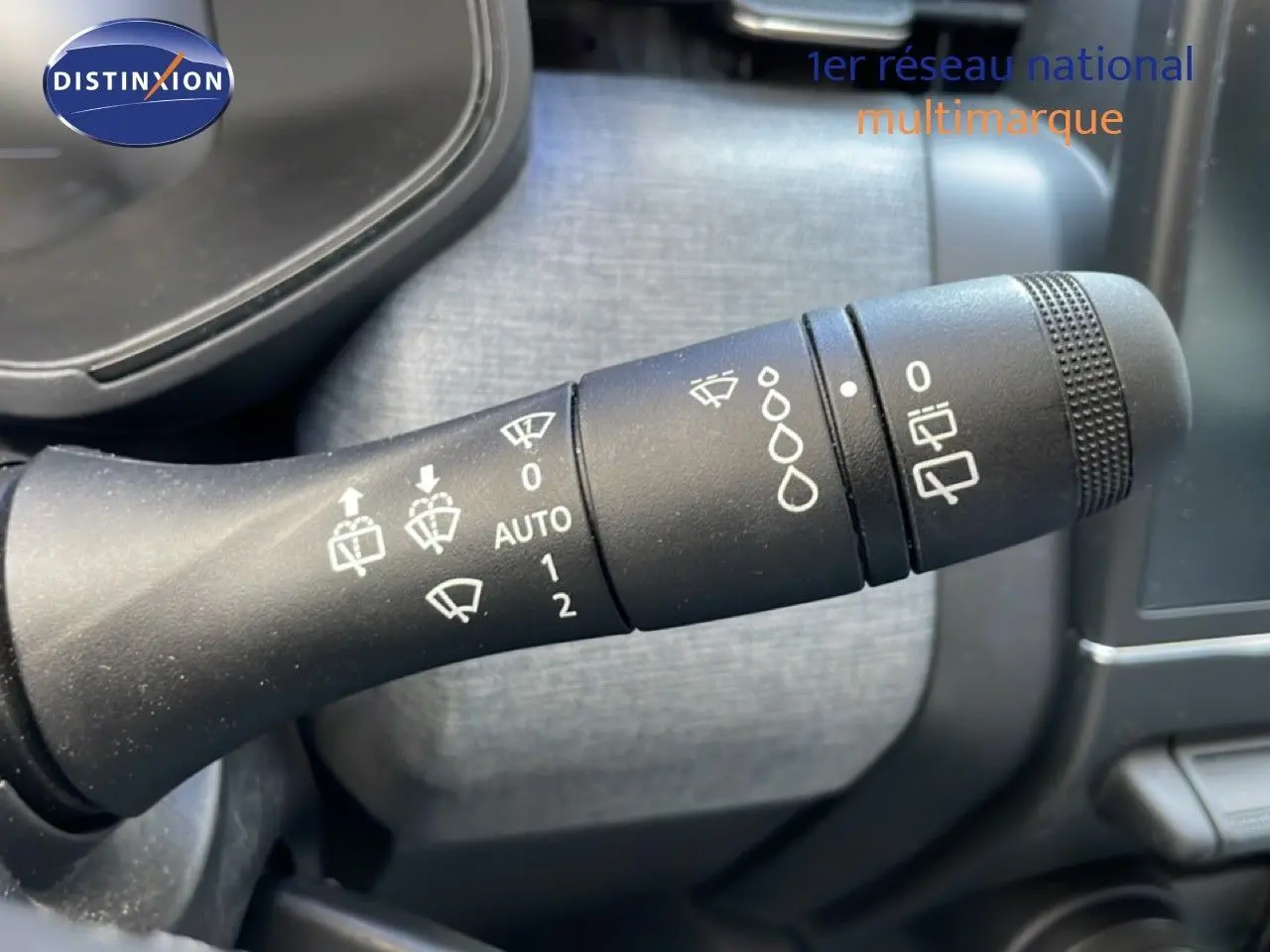 Gros plan sur la manette de commande des essuie-glaces dans l'habitacle d'une Renault Clio noire étoile métal.