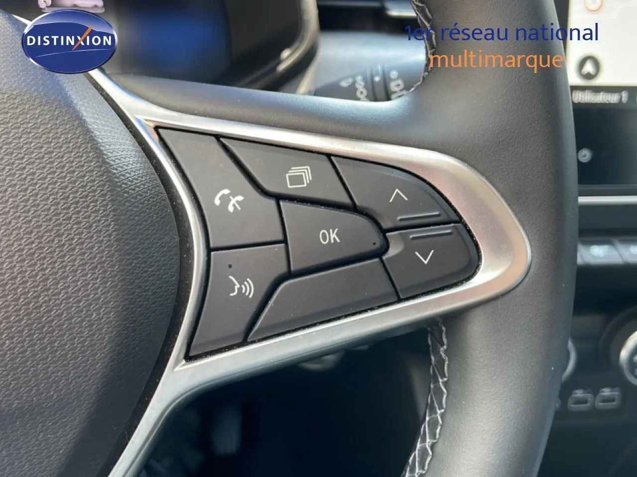 Gros plan sur les commandes multifonctions à gauche du volant cuir de la Renault Clio noire étoile métal 2025.