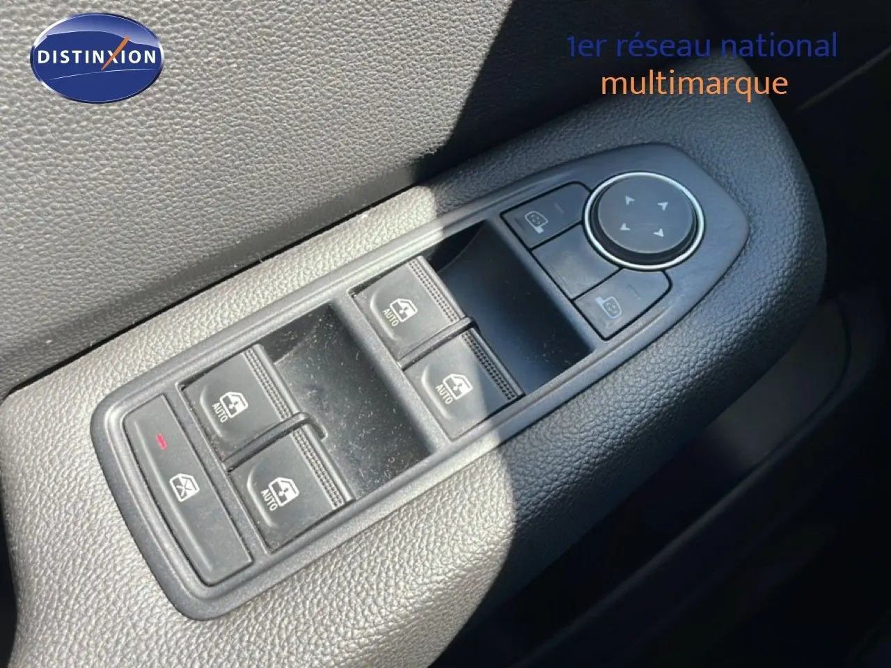 Gros plan sur les commandes des vitres électriques et des rétroviseurs sur la porte côté gauche d’une Renault Clio noire.