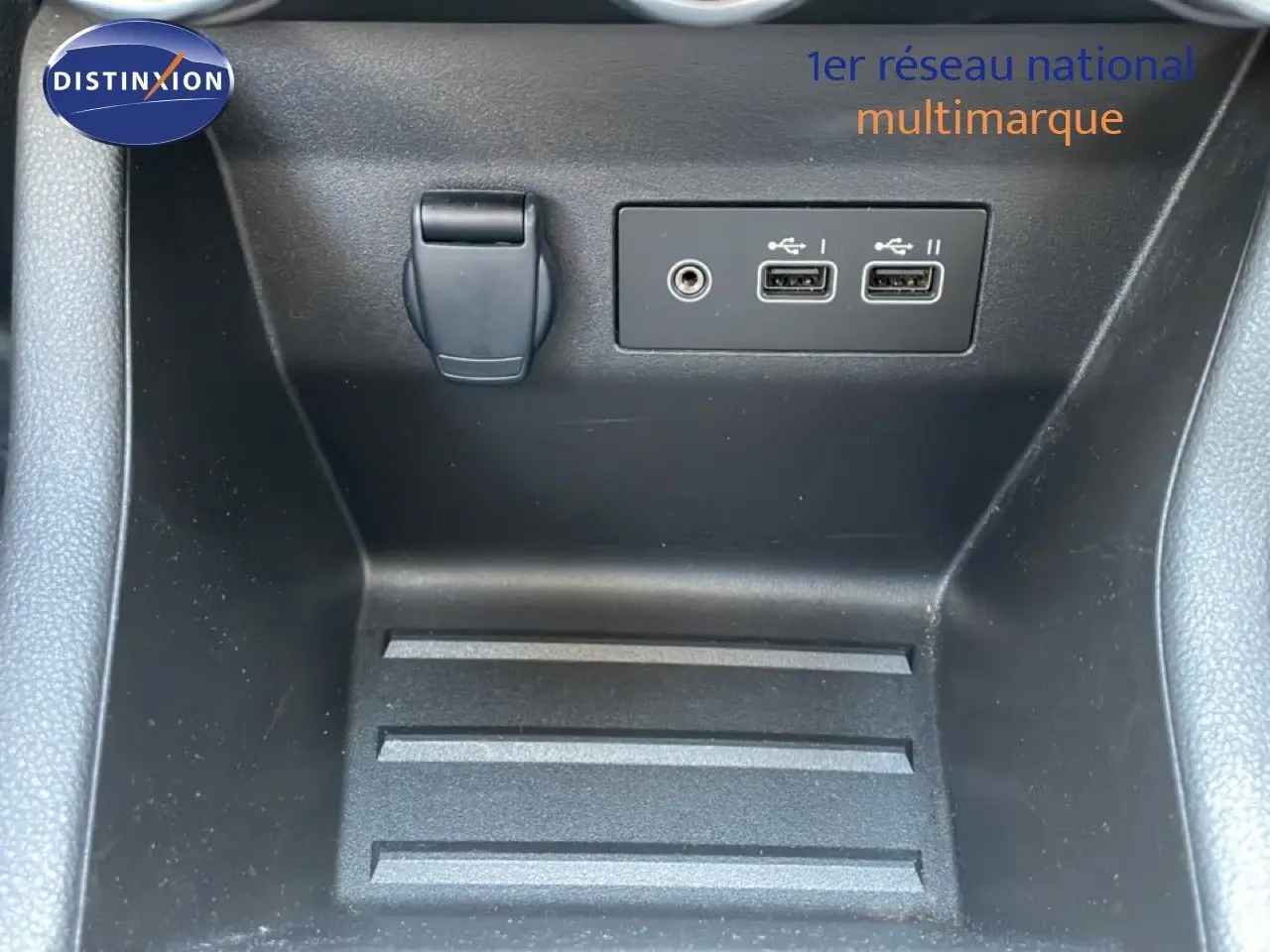 Gros plan sur la console centrale intérieure de la Renault Clio noire, montrant prises USB et prise jack.
