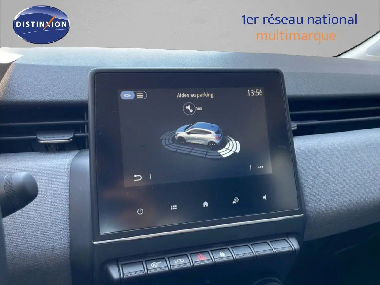 Vue rapprochée de l’écran tactile central affichant l’aide au parking dans l’habitacle gris clair d’une Renault Clio noire.