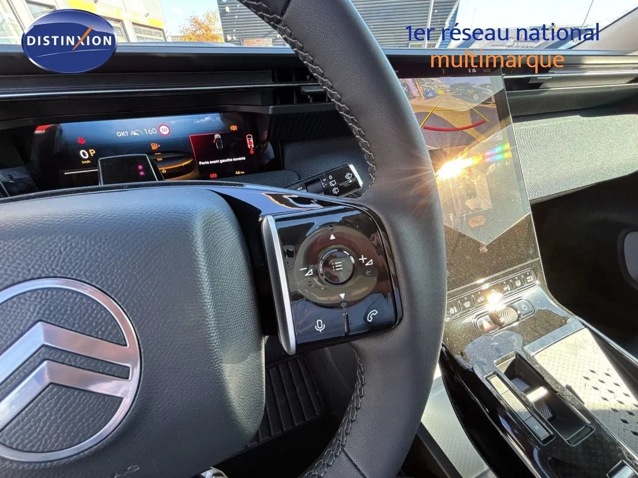 Vue intérieure centrée sur le volant et la console centrale brillante du Citroën C5 Aircross Hybrid 2026, ambiance noire élégante.