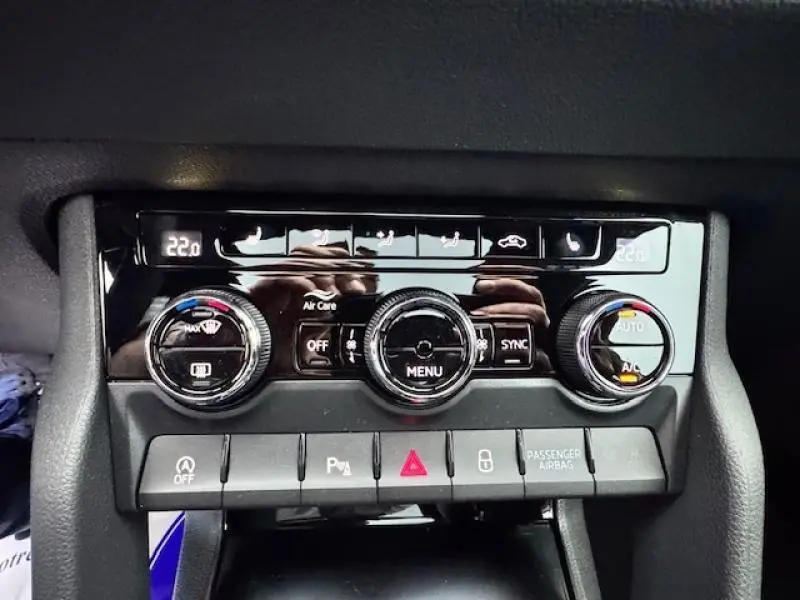 Gros plan sur la console centrale de la Skoda Karoq 2025, avec commandes de climatisation bi-zone et boutons fonctionnels noirs.