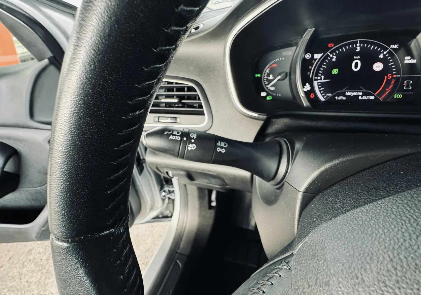 Vue rapprochée du tableau de bord et volant noir de la Renault Mégane IV Berline gris, affichage numérique au ralenti.