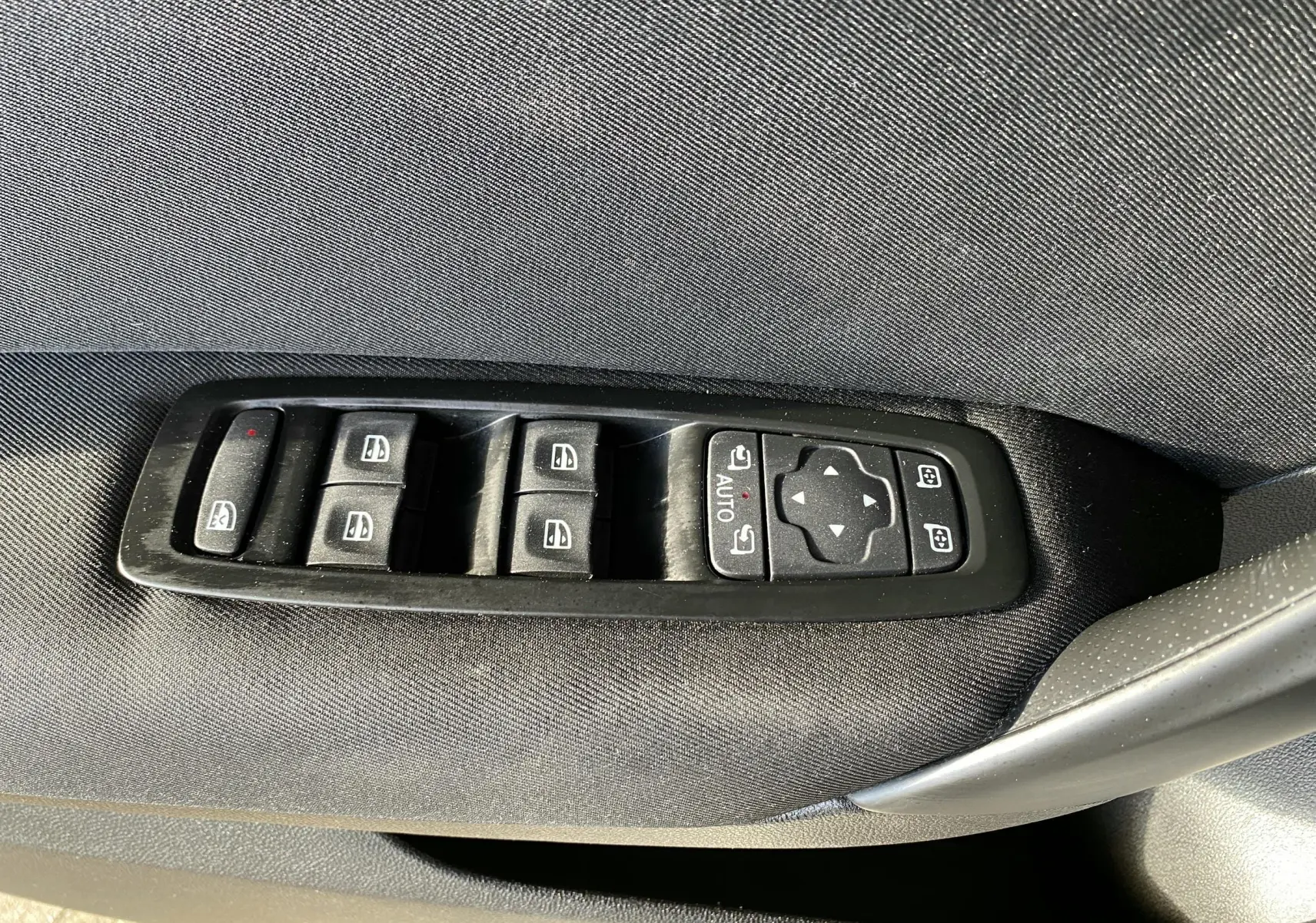 Panneau de commandes des vitres électriques et rétroviseurs sur la porte côté gauche d'une Renault Mégane IV grise.