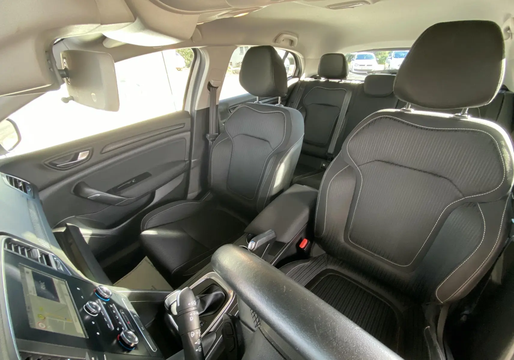 Vue intérieure avant de la Renault Mégane IV Berline 1.5 Blue dCi 115ch Business avec sièges tissu noir et console centrale visible